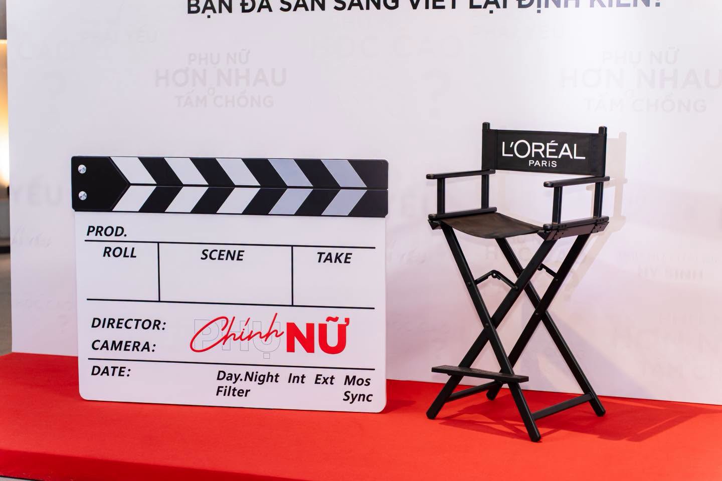 Bảng clapperboard Chính Nữ và ghế đạo diễn trước backdrop “Bạn đã sẵn sàng viết lại định kiến?”