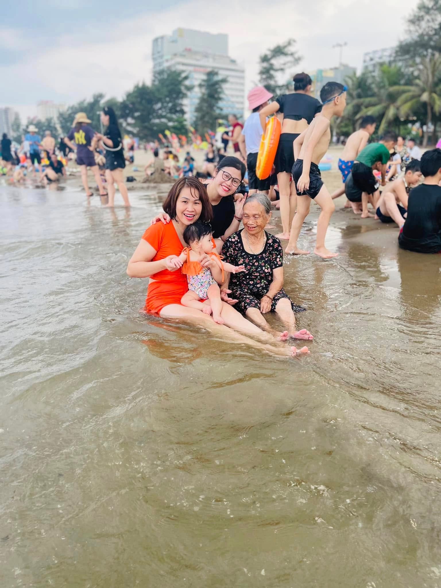 Ba thế hệ trong một gia đình ngồi cùng nhau trong làn nước biển Sầm Sơn