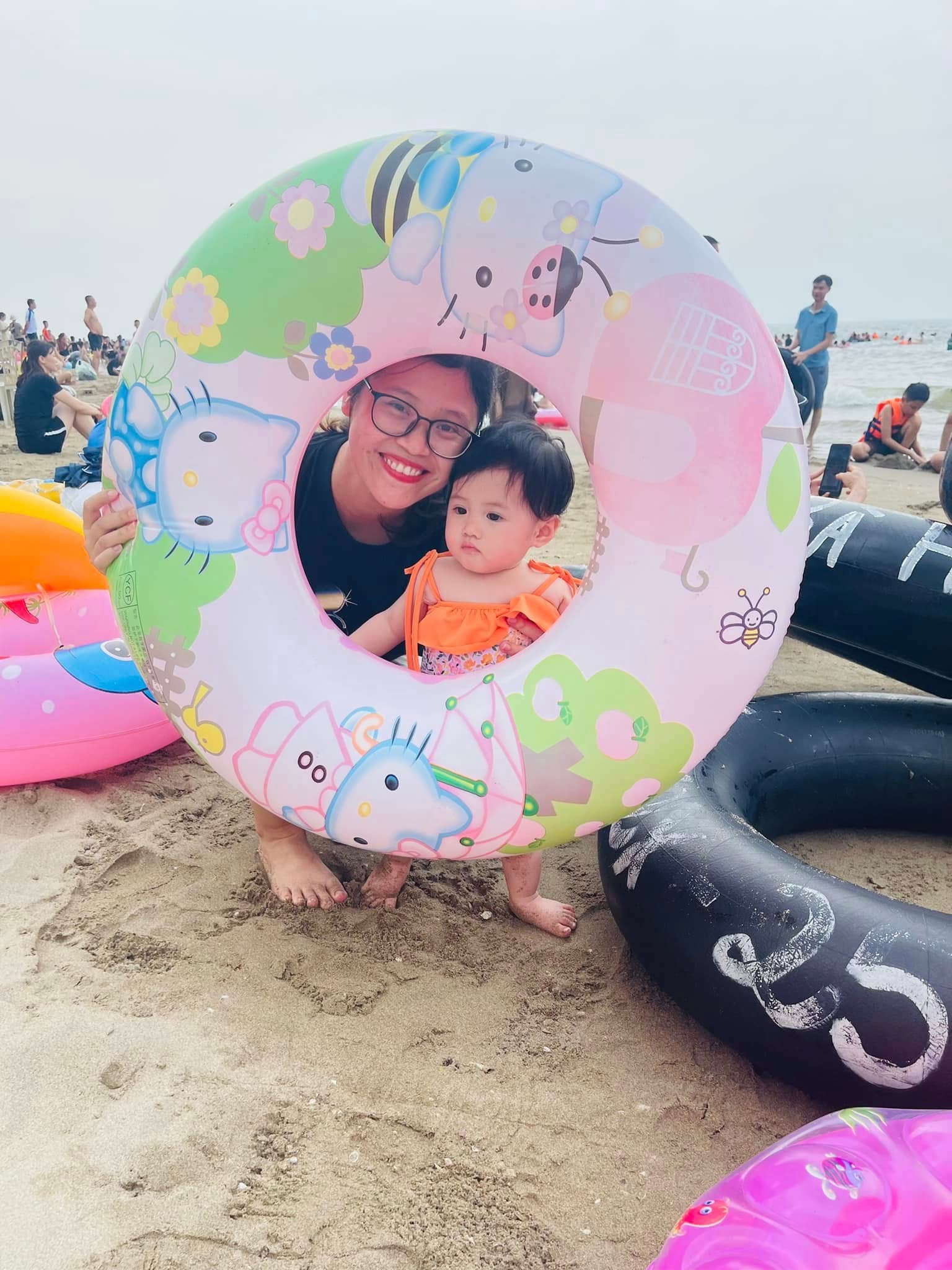 Một người mẹ và em bé chụp ảnh cùng chiếc phao bơi hình Hello Kitty trên bãi biển